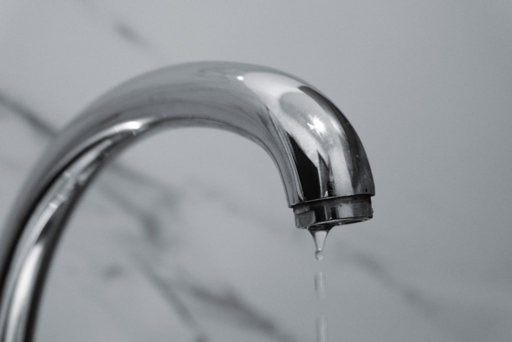 Chrome bathroom faucet dripping water