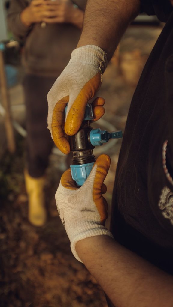 Gloved hands joining sections of a water pipe