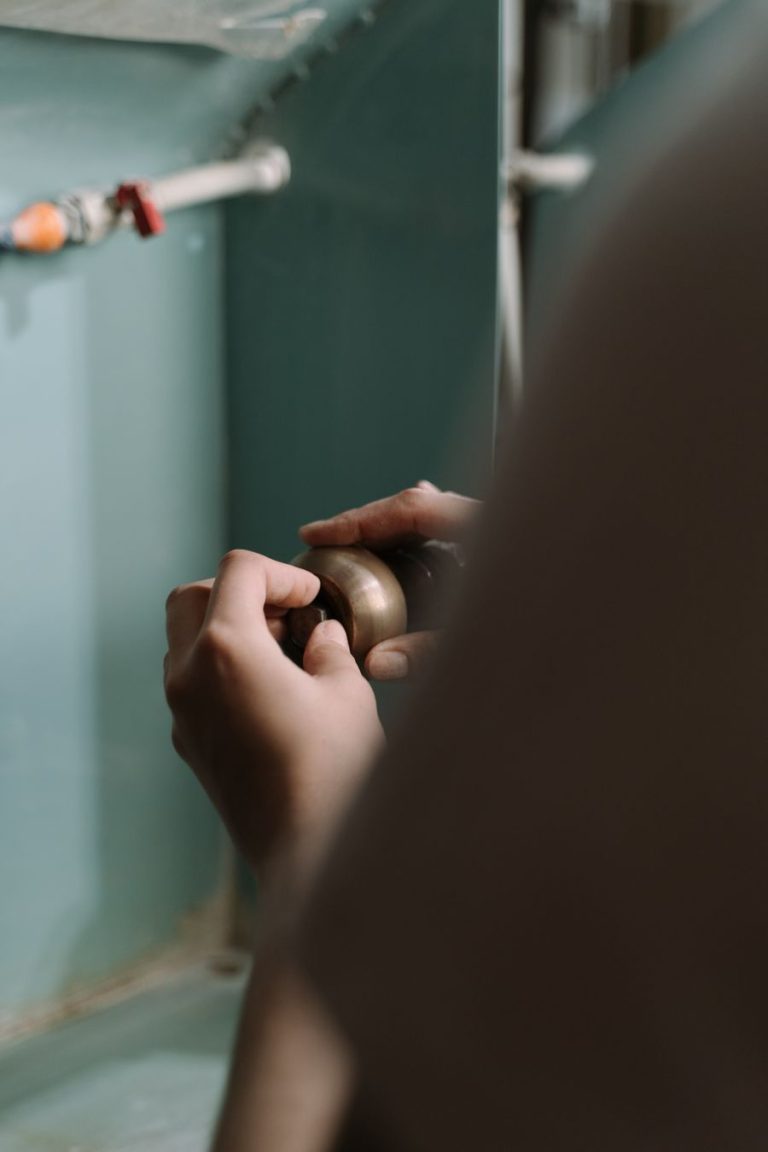 Hands adjusting a drain pipe under a kitchen sink