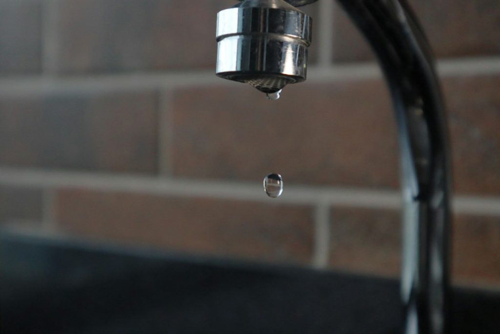 Kitchen tap with a water drop about to fall