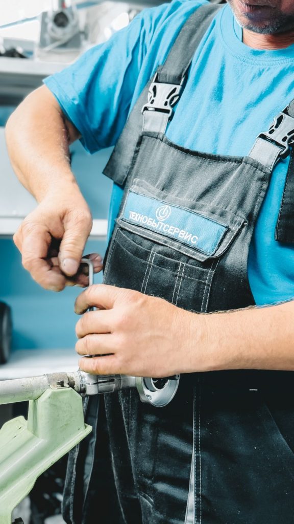 Plumber in uniform repairing a pipe with a wrench