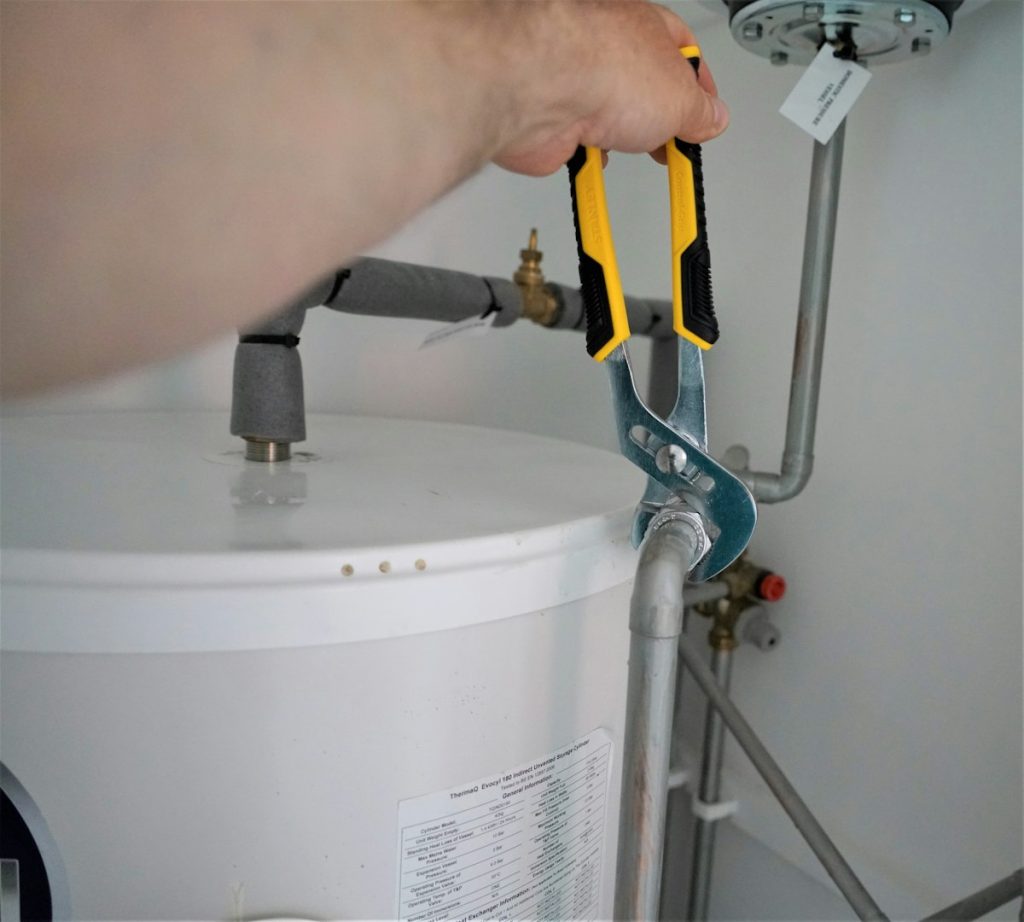 Plumber using a hand tool on a pipe connection