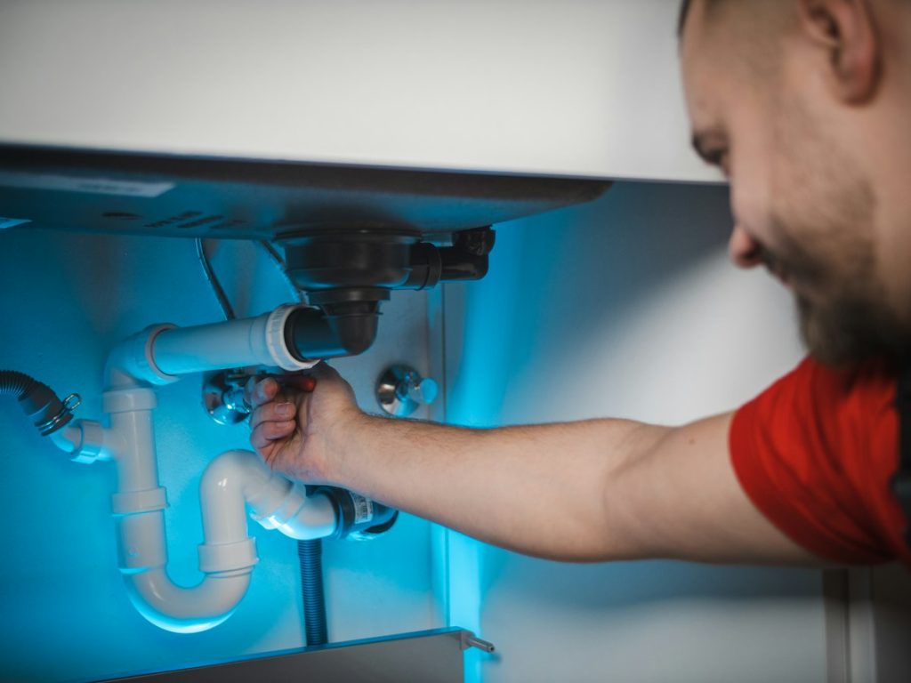 Plumber working on a water pipe exposed inside a wall