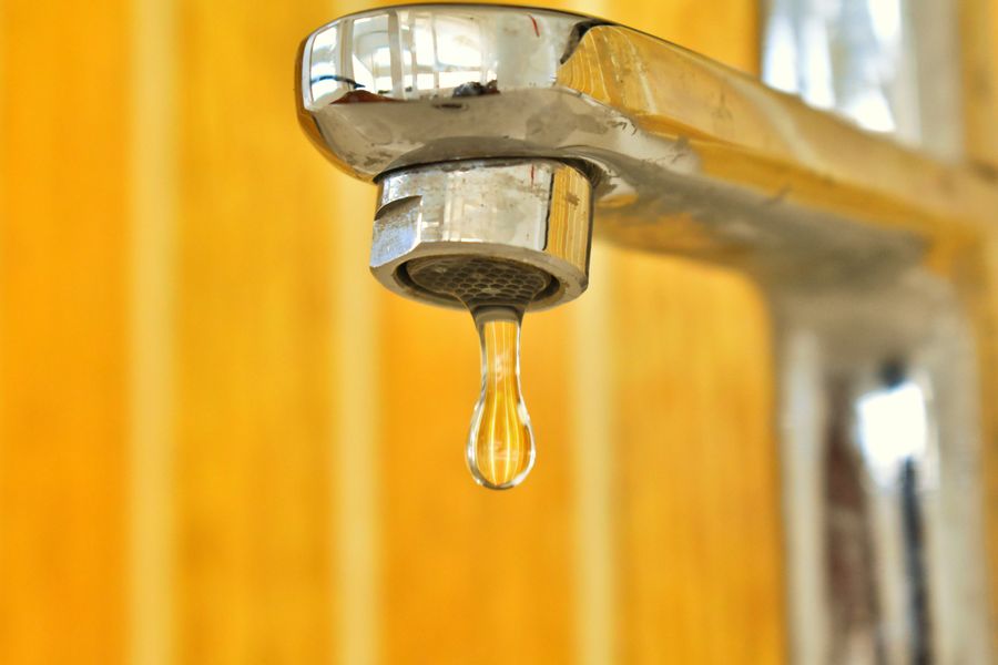 Water droplet hanging from a stainless steel faucet