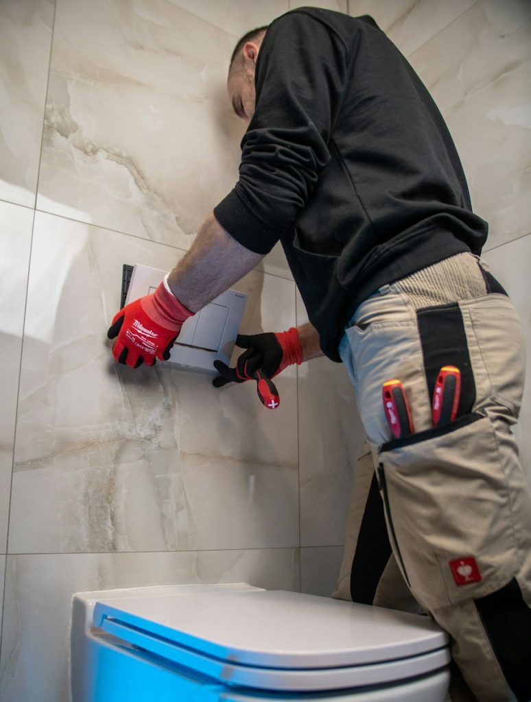 Plumber in red gloves repairing a toilet supply line