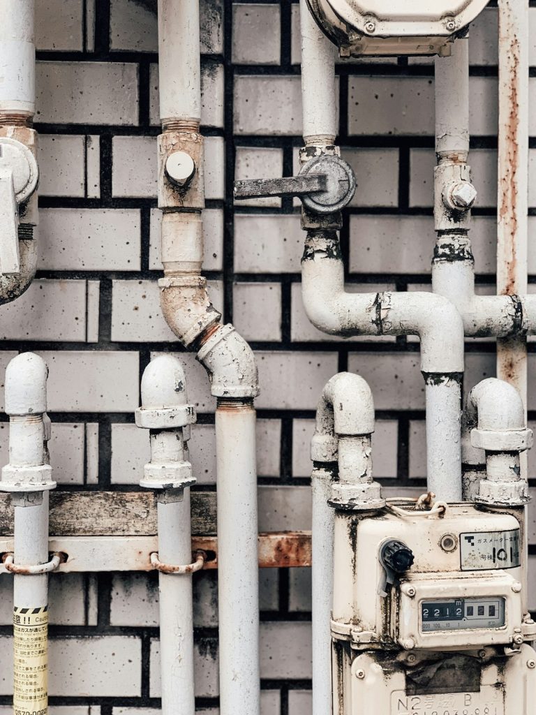 Analog water meter fitted on white supply pipes